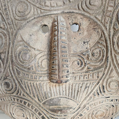 Close-Up van een handgemaakt houtden masker. Op het masker is een gezicht te zien.