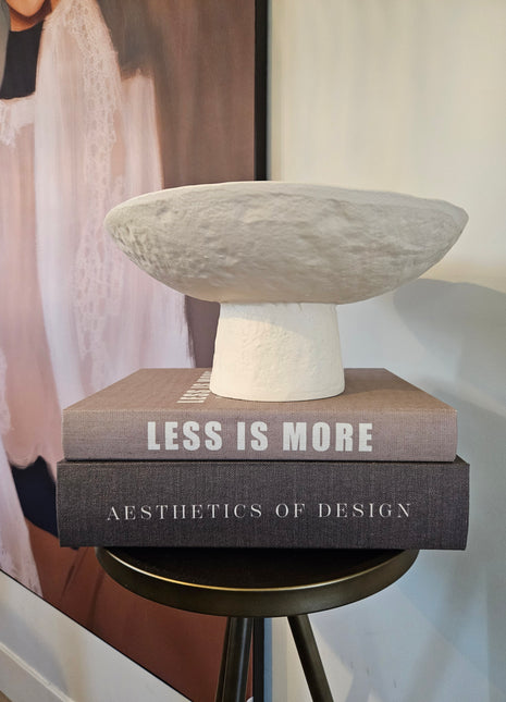 Schaal Ota crème keramiek gepresenteerd op salontafel met decoratie met een woonboek en schilderij