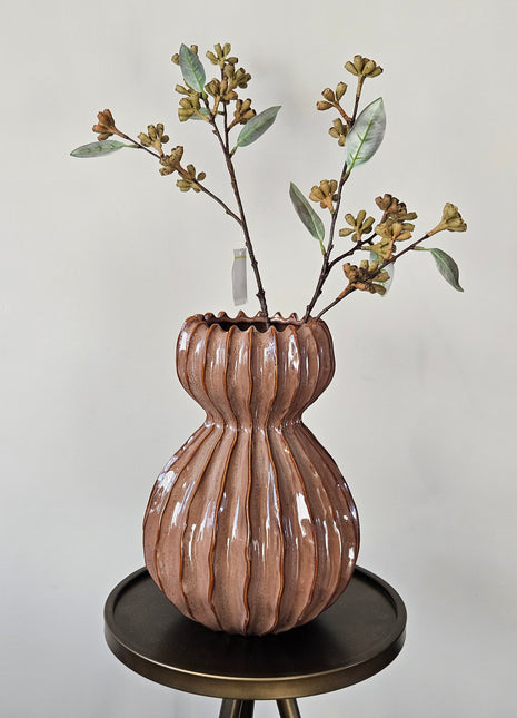Vaas Lenn Roze Keramiek gepresenteerd op een tafelblad. Organische ribbelvormen. Gepresenteerd op een tafel met takken.
