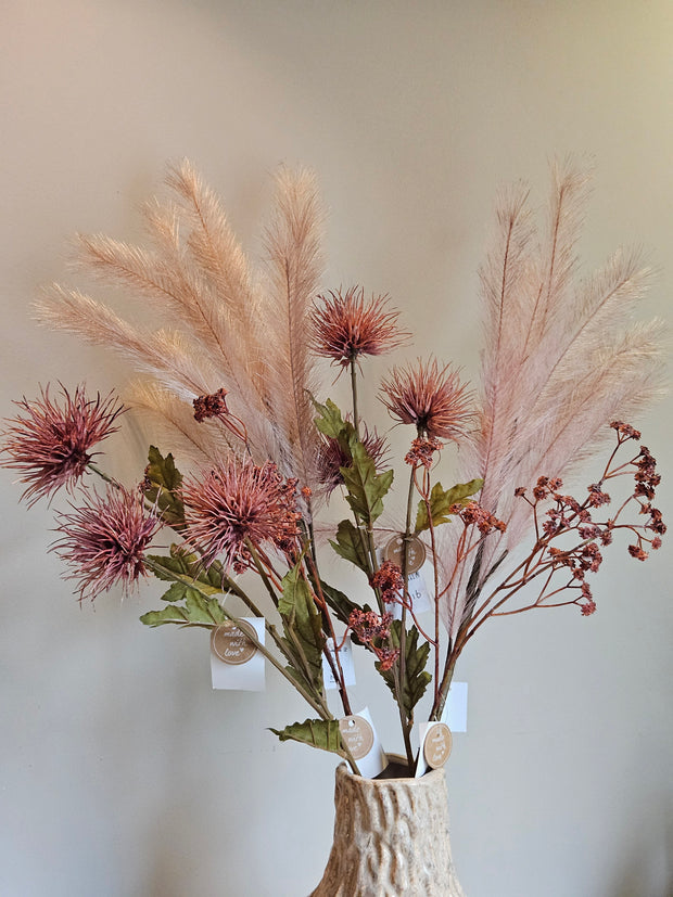 Kleurrijke bloemen staand in een vaas met organische vorm. Het is een sfeervol uiterlijk, de bloemen hebben zachte roze kleuren en natuurlijk uitziende groene bladeren. De bloemen zijn bijna niet van echt te onderscheiden