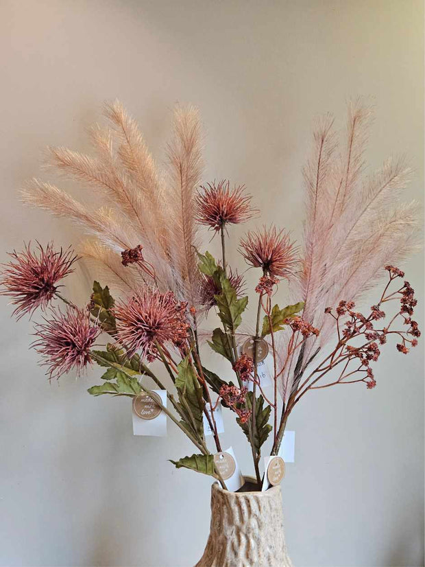 Kleurrijke bloemen staand in een vaas met organische vorm. Het is een sfeervol uiterlijk, de bloemen hebben zachte roze kleuren en natuurlijk uitziende groene bladeren. De bloemen zijn bijna niet van echt te onderscheiden