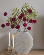 Vooraanzicht van burgundy-groen Forest Burgundy kunstboeket met stoffen bloemen in geribbelde vaas naast kaarsen