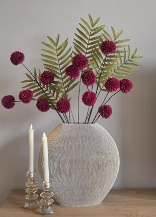 Vooraanzicht van burgundy-groen Forest Burgundy kunstboeket met stoffen bloemen in geribbelde vaas naast kaarsen