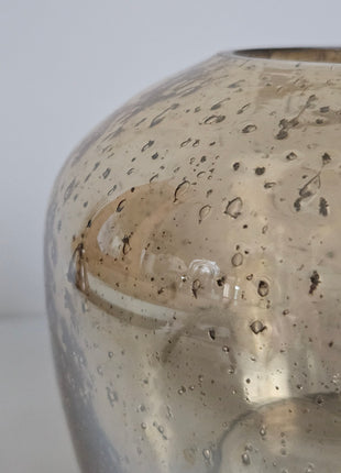 Close-up van waxinelichthouder Capira Ø 13 cm - lichtreflectie en bruin grijs glas