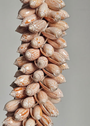 Close-up van schelpenketting roze beige - zachte tinten en ambachtelijke afwerking