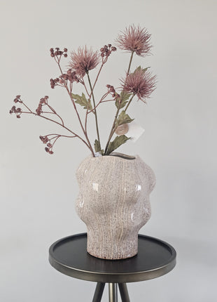 Vaas organisch zand aardewerk met natuurlijke vorm hoogte 22.5cm getoond op een bijzettafel. De vaas heeft kleurrijke bloemen.