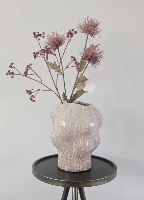 Vaas organisch zand aardewerk met natuurlijke vorm hoogte 22.5cm getoond op een bijzettafel. De vaas heeft kleurrijke bloemen.