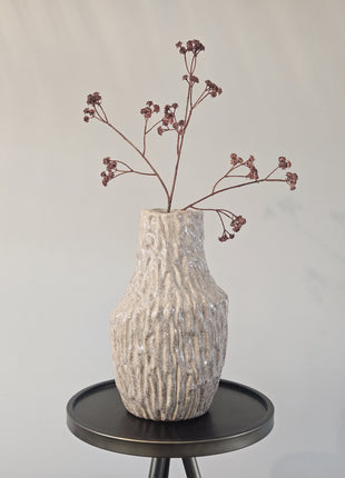 Vaas organisch zand aardewerk met natuurlijke vorm gepresenteerd een bijzettafel met kleurrijke bloemen.