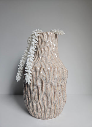 Vaas organisch zand aardewerk met natuurlijke vorm gepresenteerd met witte kunstplant