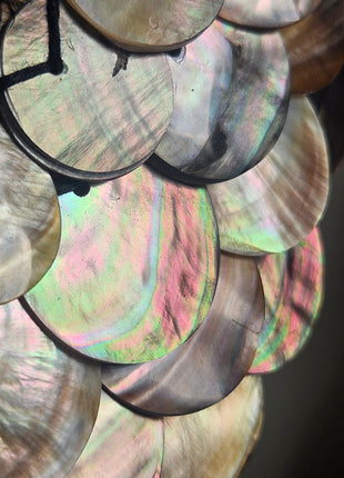 Close-up van schelpenketting met rondgepolijste schelpen en zwarte kralen - handgemaakt