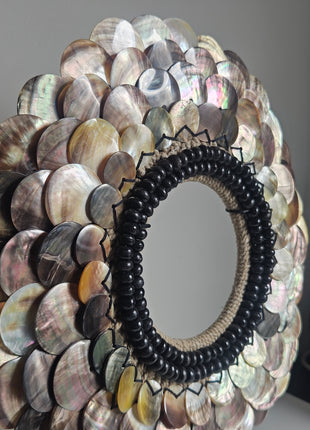 Close-up van schelpenketting met rondgepolijste schelpen en zwarte kralen - handgemaakt