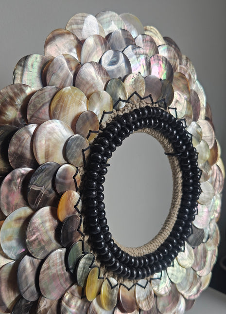 Close-up van schelpenketting met rondgepolijste schelpen en zwarte kralen - handgemaakt