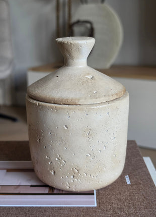 Aardewerk Potje Met Deksel Beige S in beige travertijn-achtig aardewerk met ronde knopdeksel op een koffietafelboek in een interieuromgeving