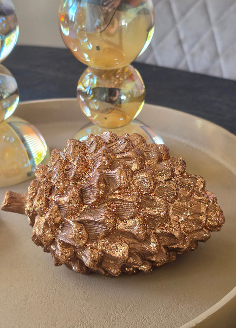 Dennenappel Catacol in crème-beige aardewerk met bruine accenten en een gekrulde steel op een dienblad met andere herfstdecoratie op een houten tafel
