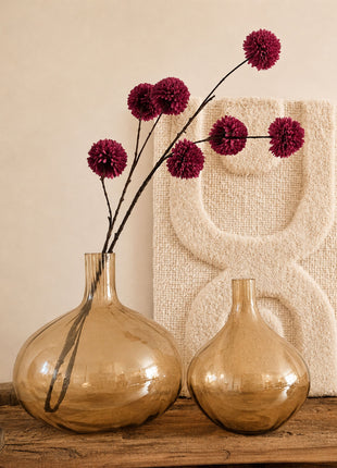 Glazen vazen bruin amber glanzend L en M naast elkaar op een houten dressoir met bordeauxrode pompom zijdetakken en een crème wandpaneel