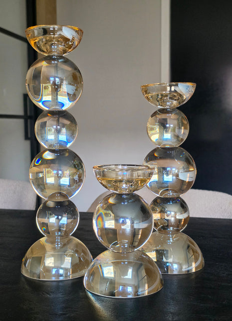 Serie kandelaars Alouette van Colmore in goud kristalglas in drie hoogtes op een donker houten oppervlak