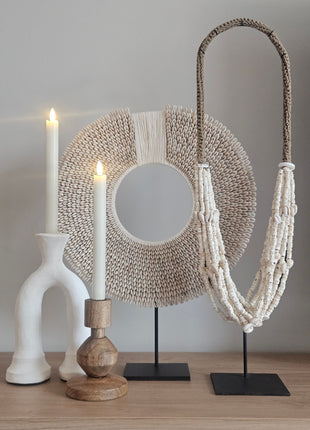 Kandelaar hout naturel met een witte kaars op een houten dressoir naast een beige keramieke pot