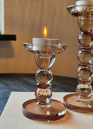 Kandelaar Opulent S in bruin kristalglas met brandend waxinelichtje op een donker houten oppervlak