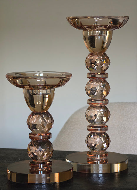 Serie kandelaars Opulent van Colmore in bruin kristalglas in drie hoogtes met brandende waxinelichtjes op een donker houten tafel