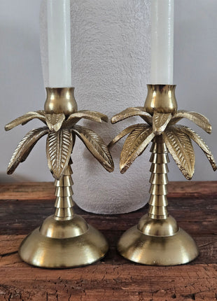 Close-up van twee kandelaars palmboom goud aluminium met een glanzende gouden afwerking en een palmblad motief