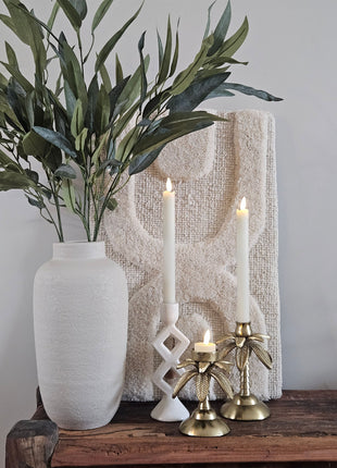 Light & Living kandelaars VIREEN zand op een houten bankje voor een schilderij met witte kaarsen en een wit koraalornament op koffietafelboeken Cosy Living en Clay Tones