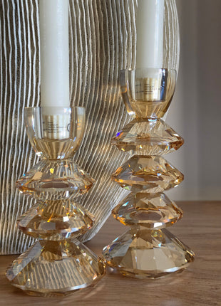 Kandelaar Rovelo in amber kristalglas met een brandende dinerkaars op een donker houten tafel