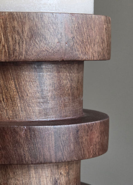 Close-up van Vail kandelaar in bruin hout met zichtbare houtnerf en ronde ringen onder een witte kaars