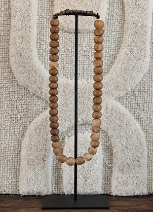 Kralenketting antique lichtbruin met ronde houten kralen op een zwart metalen standaard voor een geweven wandkleed