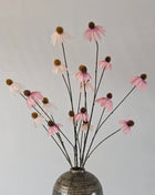 Een boeket oud roze en witte kunst-Echinacea zonnehoeden gepresenteerd in een vaas.