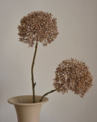 Vooraanzicht van goudkleurige Eupatorium kunsttakken met glanzende bloemschermen in een creme halsvaas