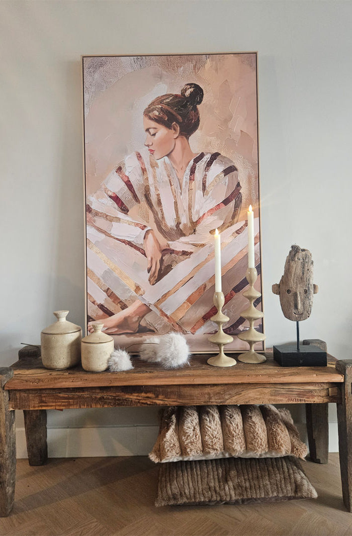 Light & Living kandelaar VIREEN zand 27cm met een witte kaars naast een houten masker ornament op een houten bankje voor een schilderij