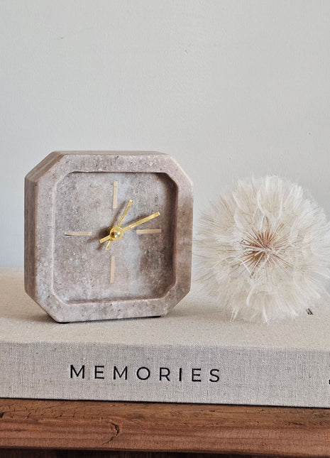 Light & Living klok PABLIA marmer zand grijs vierkant op een koffietafelboek Memories met een witte paardenbloem op een houten ondergrond