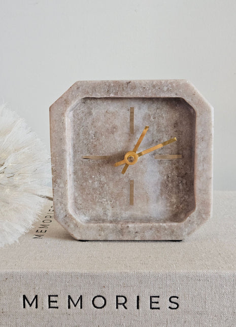 Light & Living klok PABLIA marmer zand grijs vierkant op een koffietafelboek Memories met een witte paardenbloem naast