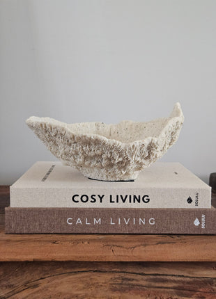 Light & Living ornament schaal Coral crème met ruwe koraalachtige structuur op koffietafelboeken "Cosy Living" en "Calm Living" op een houten ondergrond