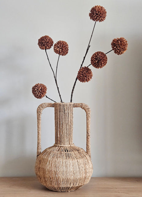 Light & Living vaas Blenza van gevlochten materiaal met handgrepen en bruine pompomtak op een dressoir