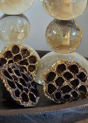 Close-up van bruin-gouden gedroogde lotuszaaddozen met glitter en ronde gaten voor glazen kandelaars op dienblad