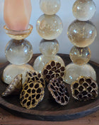 Vooraanzicht van bruin-gouden gedroogde lotuszaaddozen met glitter naast glazen kandelaars op een houten dienblad