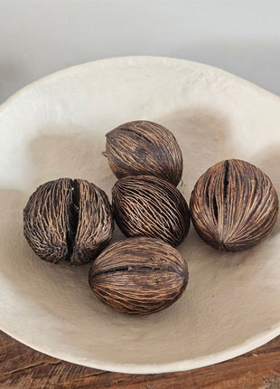 Vijf mintolla ballen in bruin in een geribbelde vezelige structuur in een witte ronde schaal op een houten ondergrond
