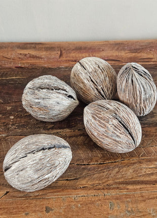 Vijf mintolla ballen in naturel met een geribbelde vezelige structuur op een donker houten ondergrond