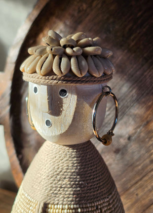 Close-up van beige Namji Doll Naya met houten gezicht en schelpenhoofdtooi voor een donker houten dienblad