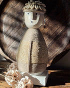 Vooraanzicht van beige Namji Doll Naya met houten gezicht en touw en kralen op een houten tafel voor een dienblad