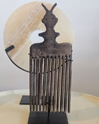 Schelpenketting op zwarte standaard naast ornament kam op zwarte standaard in donkerbruin hout op witte achtergrond