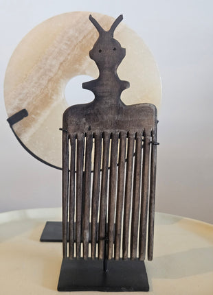 Schelpenketting op zwarte standaard naast ornament kam op zwarte standaard in donkerbruin hout op witte achtergrond