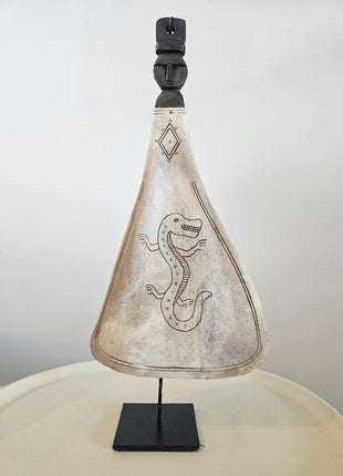 Lepel ornament naturel met gegraveerde draak op een zwarte metalen standaard op een houten ondergrond