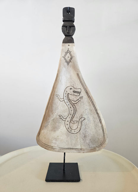 Lepel ornament naturel met gegraveerde draak op een zwarte metalen standaard op een houten ondergrond