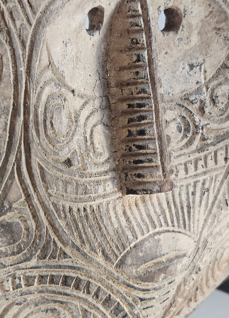 Ornament van een gezicht uitgesneden uit hout in de vorm van een masker.