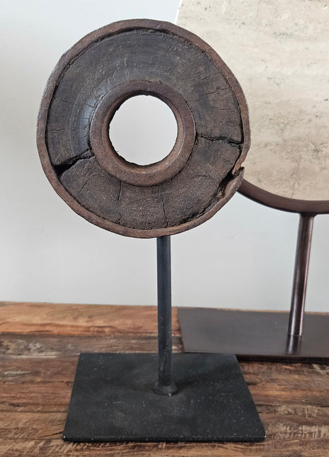 Oud houten wielnaaf ornament met een ijzeren band op een zwarte metalen standaard op een houten ondergrond
