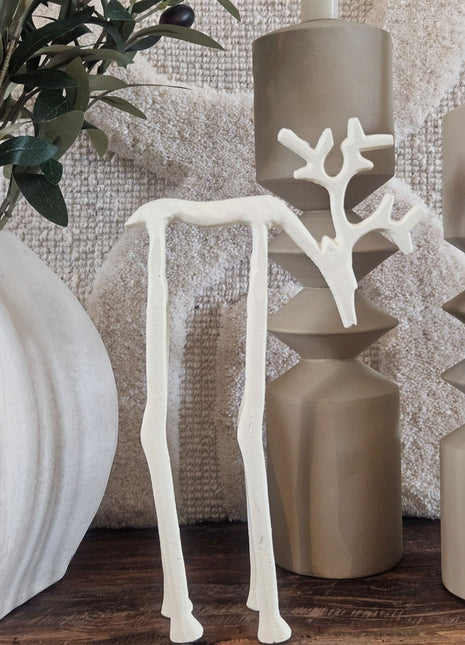 Mat crème rendierornament met gewei op een houten ondergrond naast een geribbelde aardewerk vaas Conic in beige