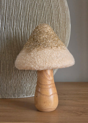 Paddenstoel Golden Glitter met een crème bouclé bovenkant met gouden glitterrand op een naturel houten steel voor een geribbelde grijze vaas op een houten tafel