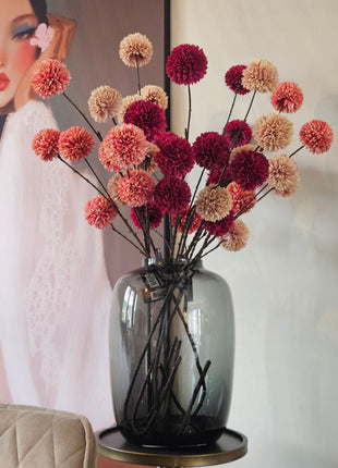 Complete glazen Vase The World Kara Tasman vaas met pompom zijdebloemen in pink, champagne en burgundy in woonkamer met schilderij op achtergrond